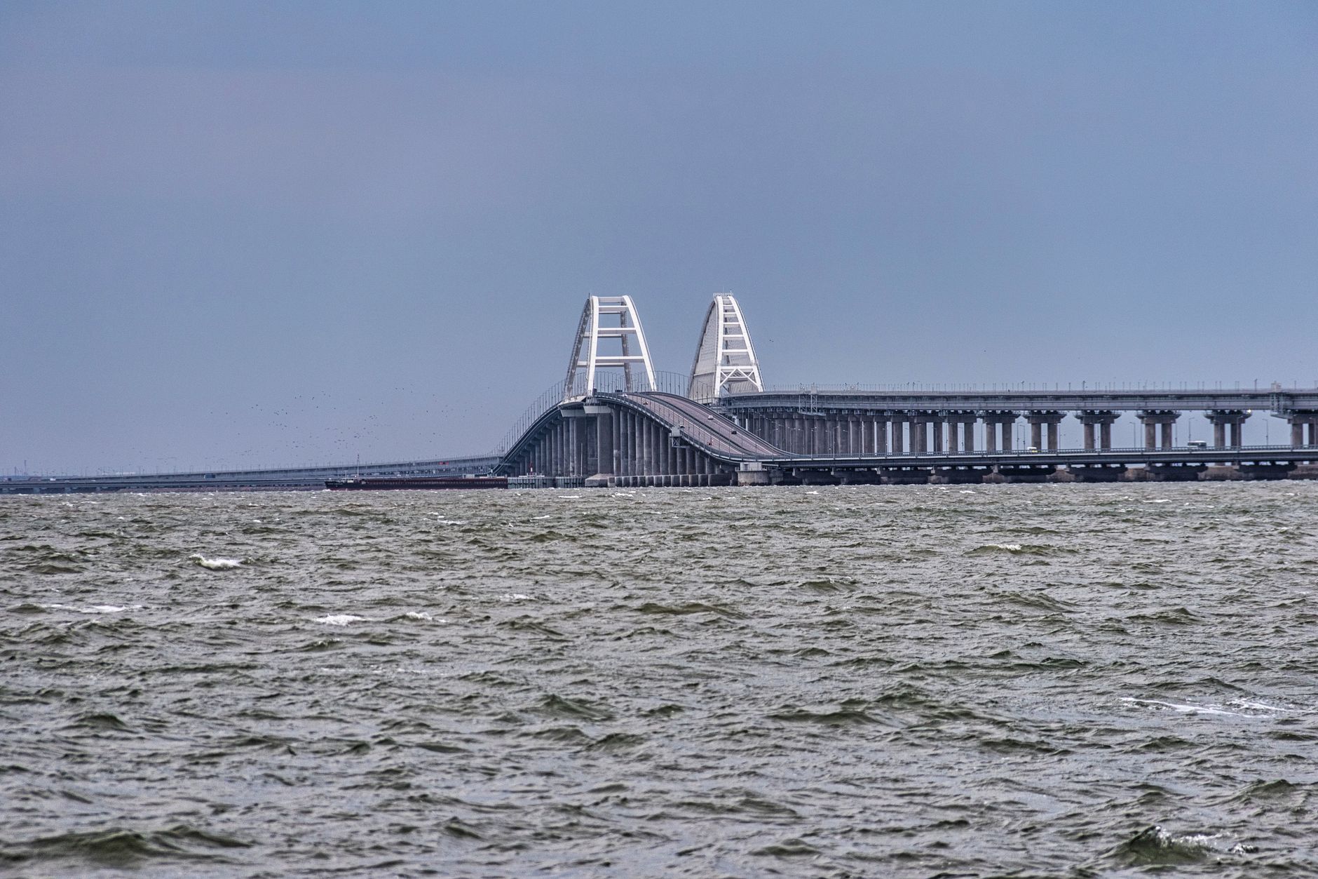 Long bridge spans choppy waters under gray skies, showcasing modern infrastructure.