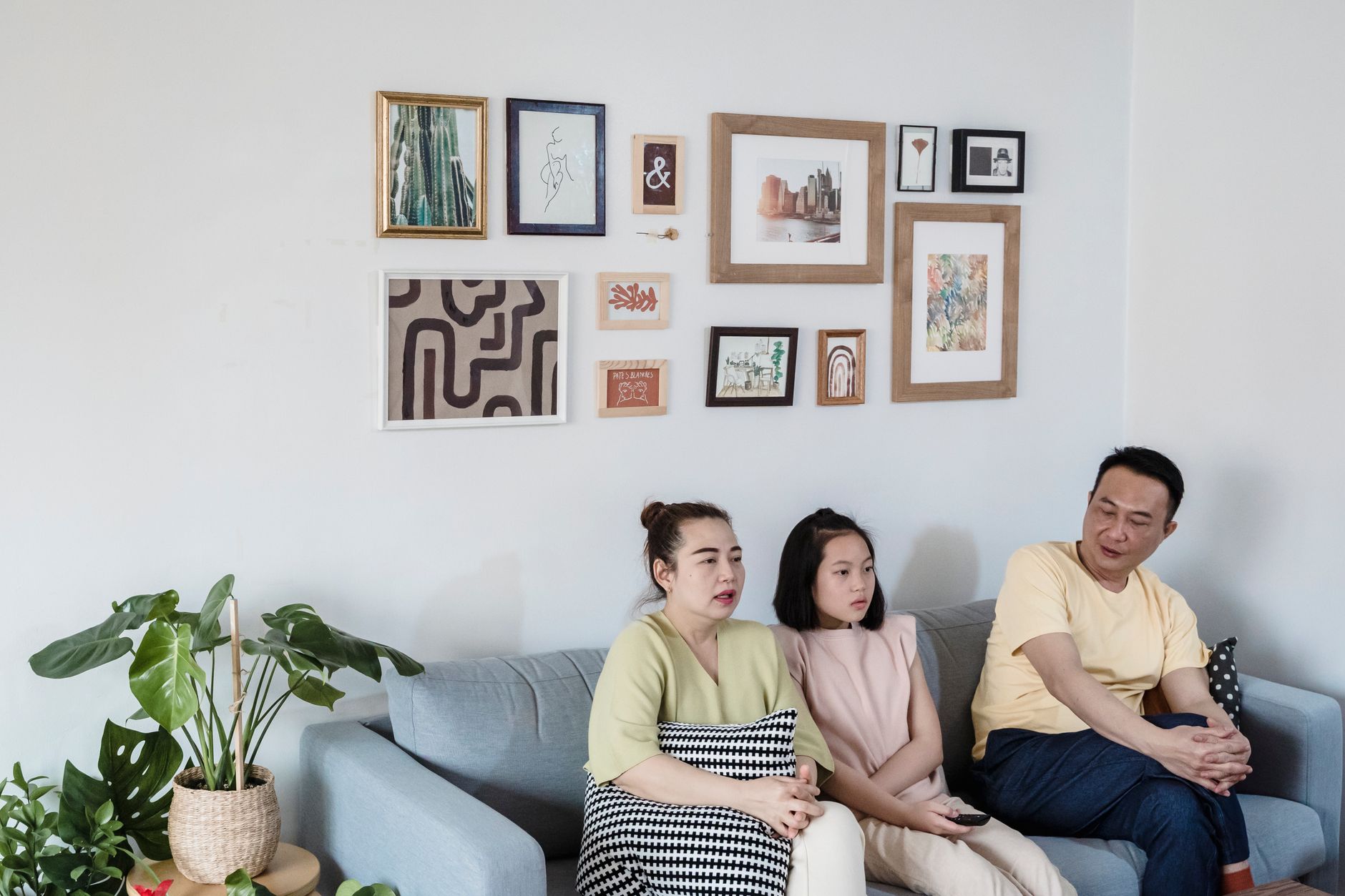 A family of three sits together on a sofa in a stylish living room, enjoying leisure time indoors.
