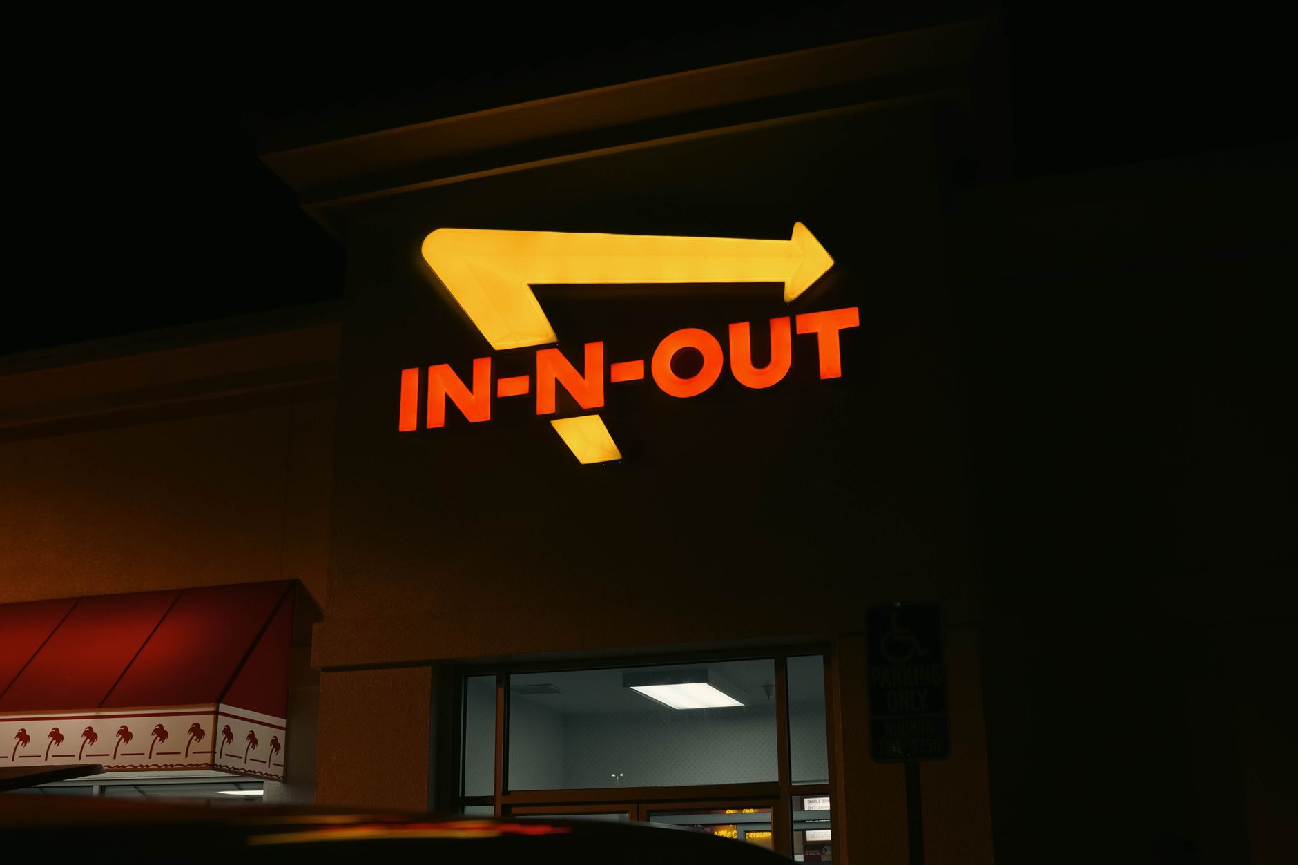 Bright neon In N Out sign glowing at night outside a restaurant in California.