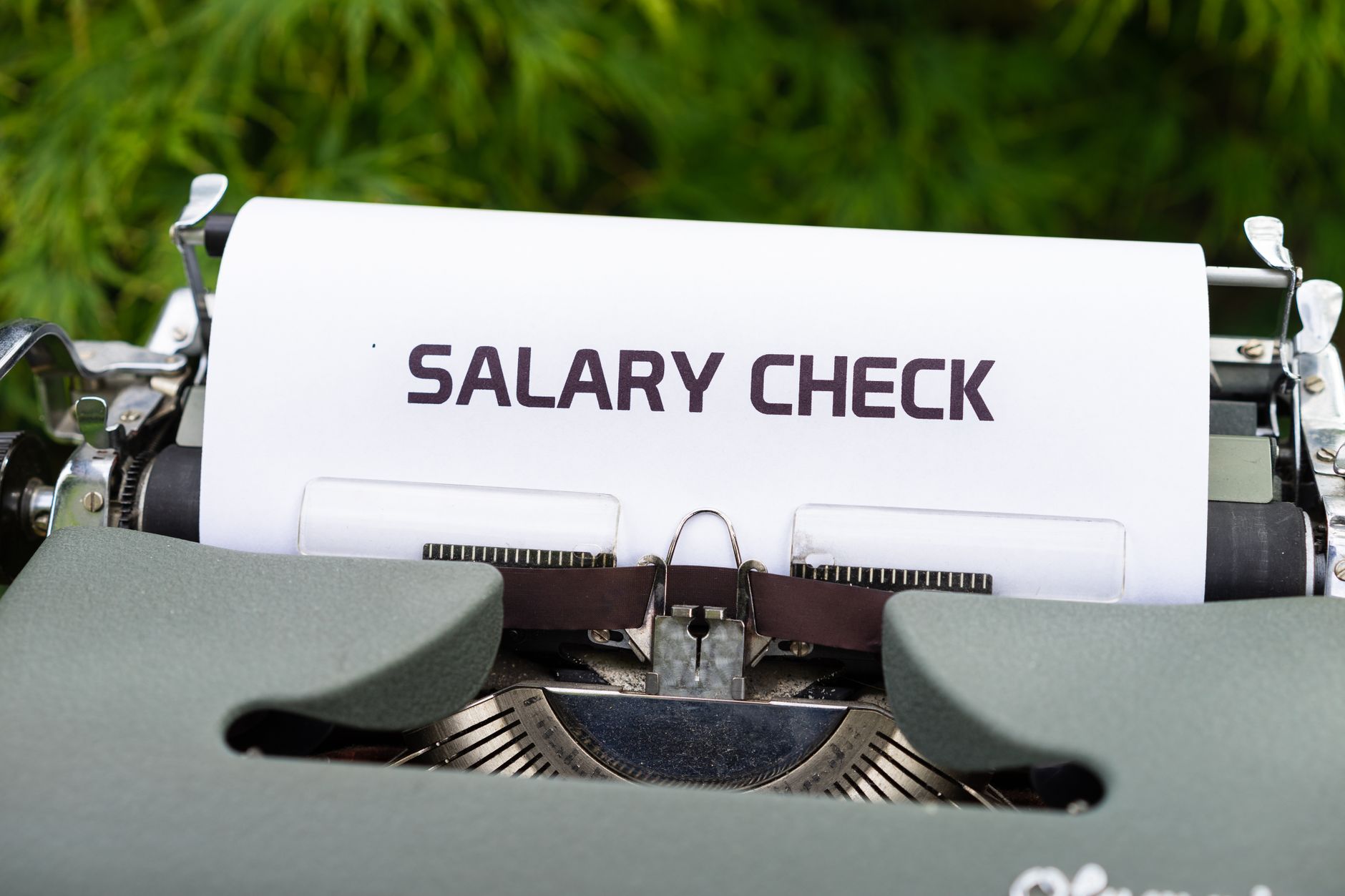 Close up of a vintage typewriter typing 'Salary Check' on paper, symbolizing payroll and finance.